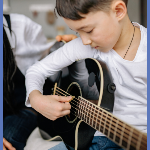 Boy using fingerpick to play black guitar